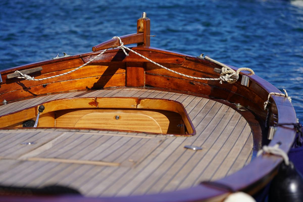 Varnished wooden deck of a classic boat above blue water