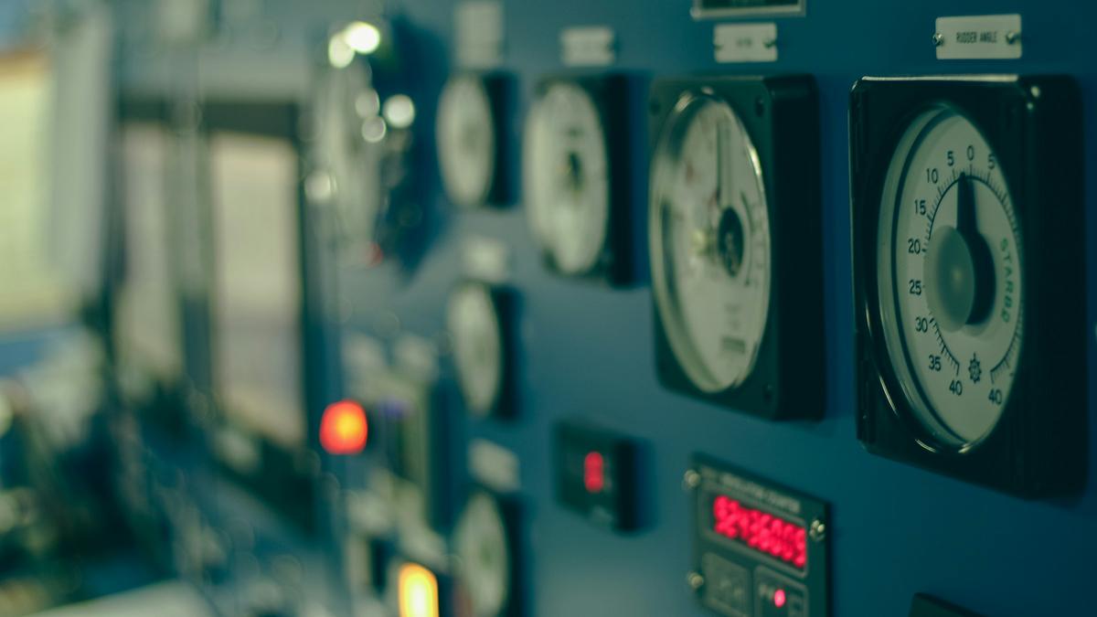 Close-up of analogue gauges and indicator lights on a machinery control console